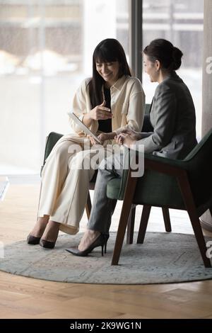 Businesswomen laughing, discuss on-line project using digital tablet device Stock Photo