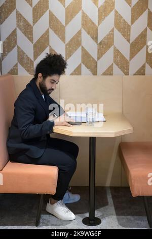Indian man in formal suit use smartphone seated in coworking Stock Photo
