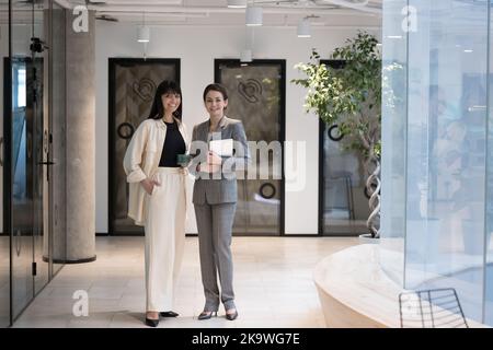 Two successful elegant businesswomen in formal suits pose in office Stock Photo