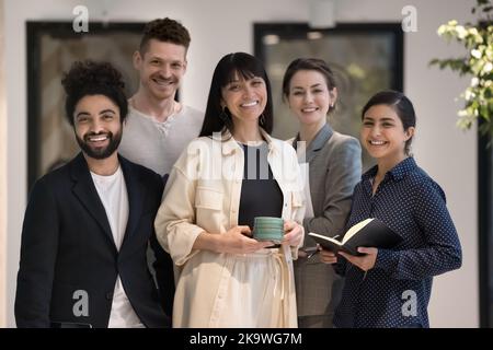 Portrait of diverse businesspeople pose standing together in office hallway Stock Photo