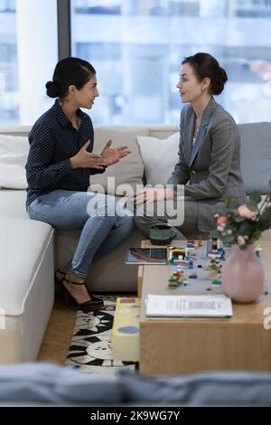 Vertical shot Indian and Caucasian businesswomen talking in office Stock Photo