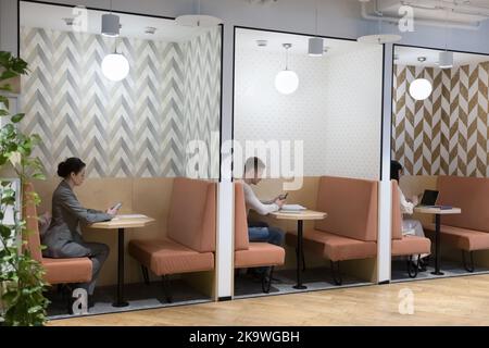 Three busy employees working seated in coworking space with partitions Stock Photo