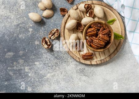 Nuts and seeds, healthy fats, various trace elements and vitamins. Bowl with pecan nuts on a stone table. View from above. Copy space. Stock Photo