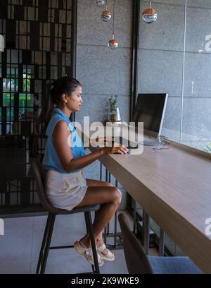Thai Asian women working on a computer desk in a hotel lobby. Women behind screen Stock Photo