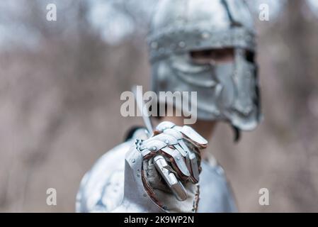 Noble warrior. Portrait of one medeival warrior or knight in armor and helmet with shield and sword posing isolated over dark background. Stock Photo