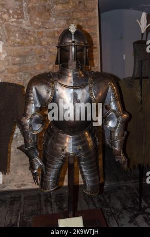 Noble warrior. Portrait of one medeival warrior or knight in armor and helmet with shield and sword posing isolated over dark background. Stock Photo