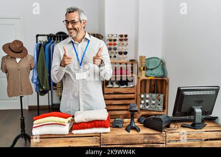 Middle age hispanic man working as manager at retail boutique pointing fingers to camera with happy and funny face. good energy and vibes. Stock Photo