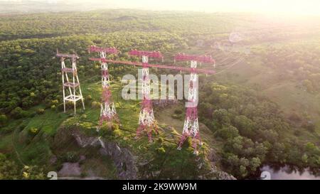 High voltage post.High-voltage tower sun beam. High voltage power lines on rock. Electricity distribution station. Voltage electric transmission tower Stock Photo