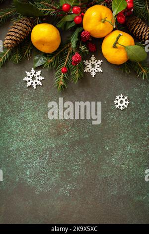 Winter composition with fir branches, cones and tangerines on a stone background. Seasons greeting card. View from above. Copy space. Stock Photo