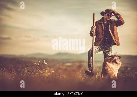Caucasian Cowboy with a Garden Fork in His Hand Staying in Front of His Family Owned Farmland Stock Photo