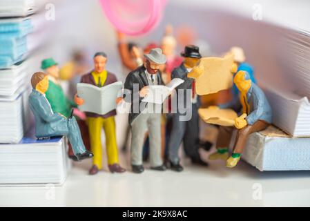 Miniature toy of passengers read newspaper and people travel from work on a public transport concept - travel on a train or bus. Stock Photo