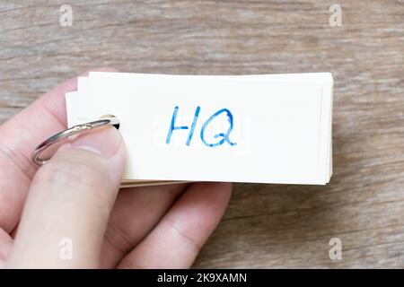 Hand hold flash card with handwriting in word HQ (Abbreviation of headquarters) on wood background Stock Photo