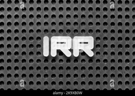 White alphabet letter in word IRR (Abbreviation of internal rate of return) on black pegboard background Stock Photo