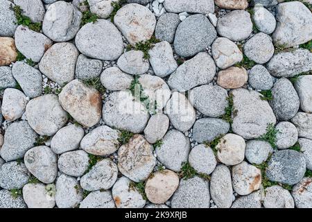 Pavement from cobblestone with sprouted grass. View from above. Stock Photo
