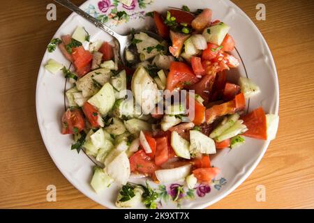 Fresh salad with tomatoes, cucumbers and onion in the plate Stock Photo