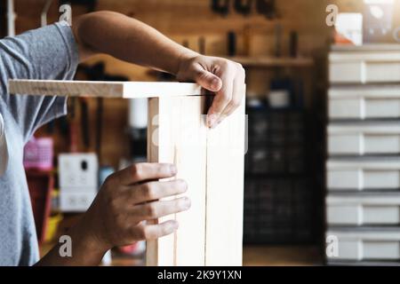 A carpenter measures the planks to assemble the parts, and build a wooden table for the customer. Stock Photo