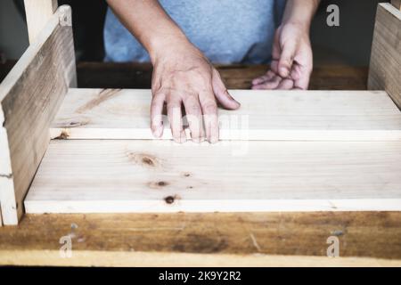 A carpenter measures the planks to assemble the parts, and build a wooden table for the customer. Stock Photo