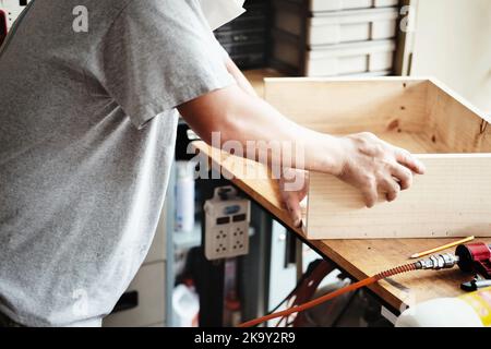 A carpenter measures the planks to assemble the parts, and build a wooden table for the customer. Stock Photo