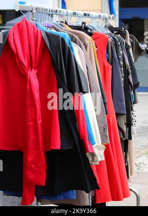 vintage used clothes and new dresses in the stall at the flea market Stock Photo