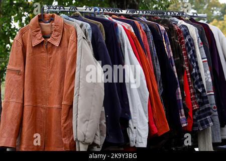 vintage used clothes and new dresses in the stall at the flea market Stock Photo