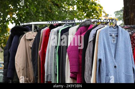 vintage used clothes and new dresses in the stall at the flea market Stock Photo