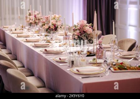 Elegant decoration of the table in restaurant. Pink tablecloth stylish cutlery and beautiful flowers Stock Photo
