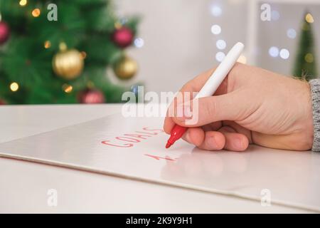 A man writes his goals and plans on a marker board for New Year and Christmas. Stock Photo