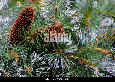 Close-up of an artificial Christmas tree with glitter frost, snow and cones as a Christmas background. Copy space Stock Photo