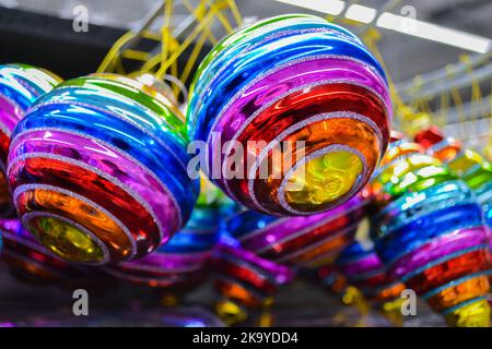 Close up of bright glass rainbow colored Christmas balls, baubles hanging for sale. The concept of the holiday, Christmas, symbol of the rainbow Stock Photo