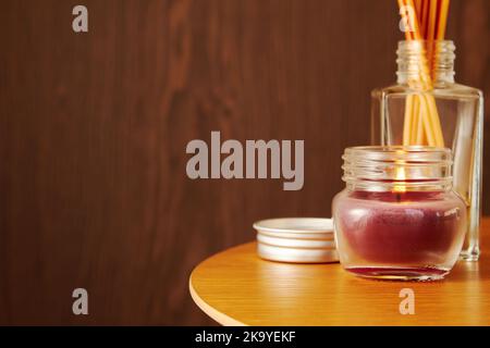 Scented aroma candles, perfume and sticks on the wooden table. Cozy interior and atmosphere for relaxation. Copy space for advertisement Stock Photo