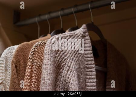 close up of pastel warm knitted cardigan sweater hanging in the closet Stock Photo