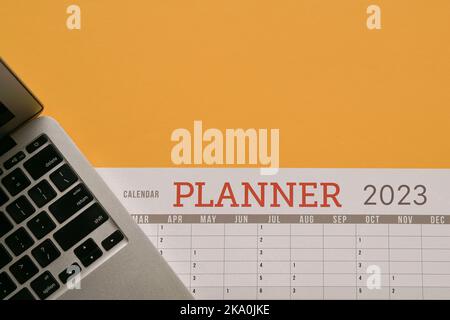 2023 Planner Calendar with computer laptop. Top view, copy space. Stock Photo