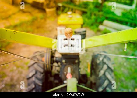 Gear lever on a walk-behind tractor close-up on a blurred background. Control elements of agricultural machinery. Rototiller connection and gear shift Stock Photo