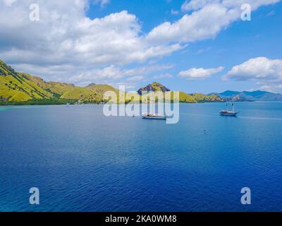 Aerial shot of beautiful blue lagoon at hot summer day with sailing boat. Komodo Island (Komodo National Park), Labuan Bajo, Flores, Indonesia Stock Photo