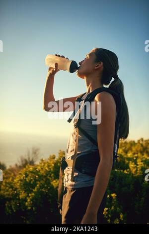 Better keep my energy levels up along this hike. a young woman taking a break while out on a hike through the mountains. Stock Photo