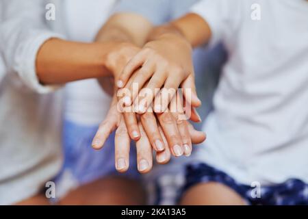 Were in this, together. Closeup shot of an unrecognizable family of three with their hands in a pile. Stock Photo