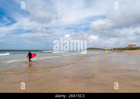 Newquay, United Kingdom - 4 Spetember, 2022: surfer with pink surfboard heads into the water to catch many great waves at Fistral Beach in Newquay Stock Photo