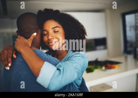Im holding on and not letting go. a cheerful young couple holding each other and sharing a tender moment in the kitchen at home during the day. Stock Photo