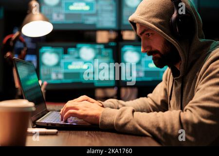 Programmer thief hacking security system on computer, using development malware to steal big data from server. Working at night with multiple monitors to hack important information, cybercrime. Stock Photo