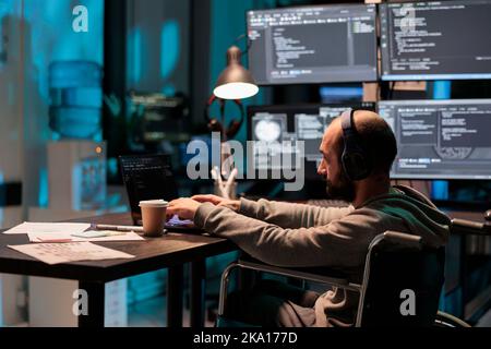 Software developer with chronic disability writing code, computing big data to create app interface. Using html script and database source to program artificial intelligence algorithm. Stock Photo