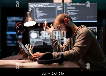 Thoughtful programmer brainstorming ideas about coding solution, finding algorithm to create database script. Feeling pensive and thinking about software developing system late at night. Stock Photo