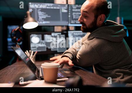 Database programmer writing code on multiple screens displaying artificial intelligence algorithm late at night. Programming online cloud computing on monitors to develop new html script. Stock Photo