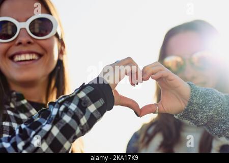 Its all love. Cropped portrait of two attractive young women making a heart shape with their hands while outdoors. Stock Photo