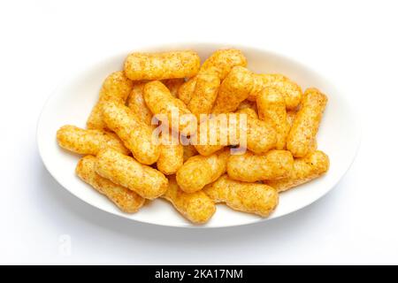 Peanut flips, in a white bowl. Also known as Bamba, peanut puffs or snips, is a puffed, peanut-flavored corn snack. Stock Photo