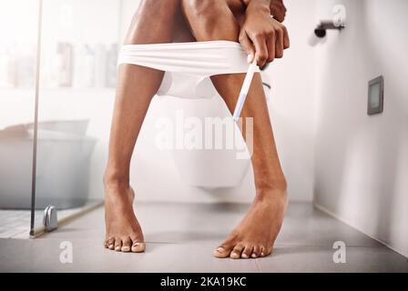 Baby fever is officially in full swing. an unrecognizable woman taking a pregnancy test while sitting on the toilet. Stock Photo