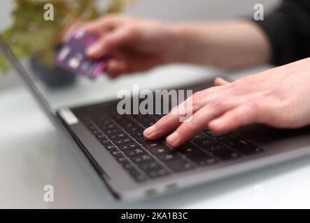 File photo dated 30/03/20 of a woman using a laptop as she holds a bank card. A big proportion of consumers have turned to financial tools like credit cards and overdrafts to help supplement their income amid cost-of-living pressures, according to a new survey. Stock Photo