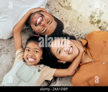 Love, floor and portrait of relax happy family having fun, bond and enjoy quality time together while lying on ground carpet. Happiness, big smile and Stock Photo