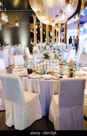 Luxury decor in restaurant. Round table with different elements of decor. Beautiful flowers and table setting Stock Photo