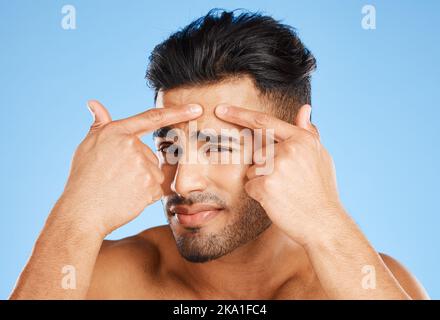 Skincare, confused and portrait of acne man with hands on face feeling pimple with anxiety, doubt and stress. Model in studio analyzing skin with Stock Photo