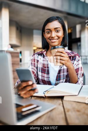Coffee and social media gets her through college life. a young female student using a cellphone outside on campus. Stock Photo